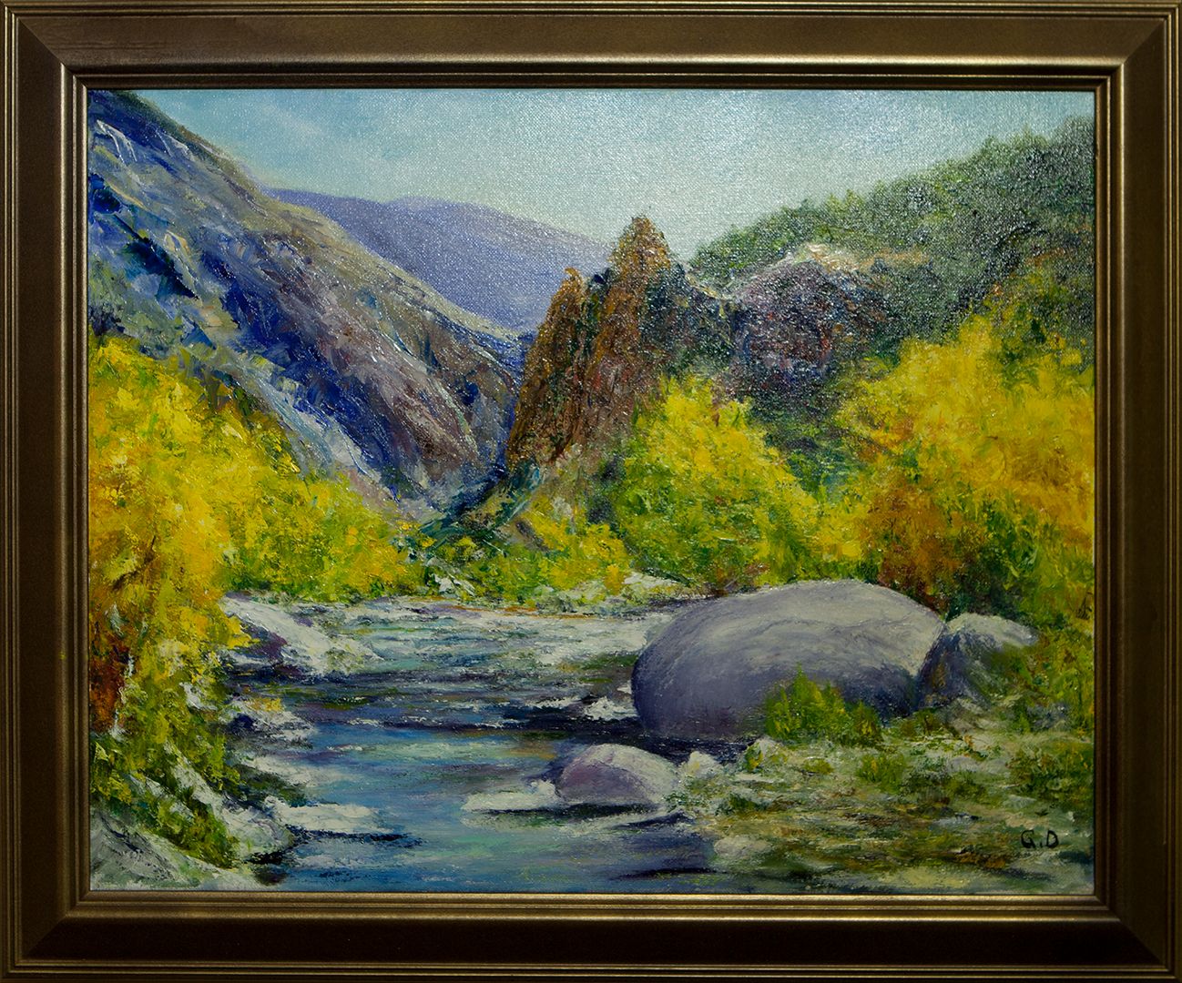 A river tumbling over large boulders through a canyon, framed by bright yellow autumn trees and a tall pinnacle of rock.