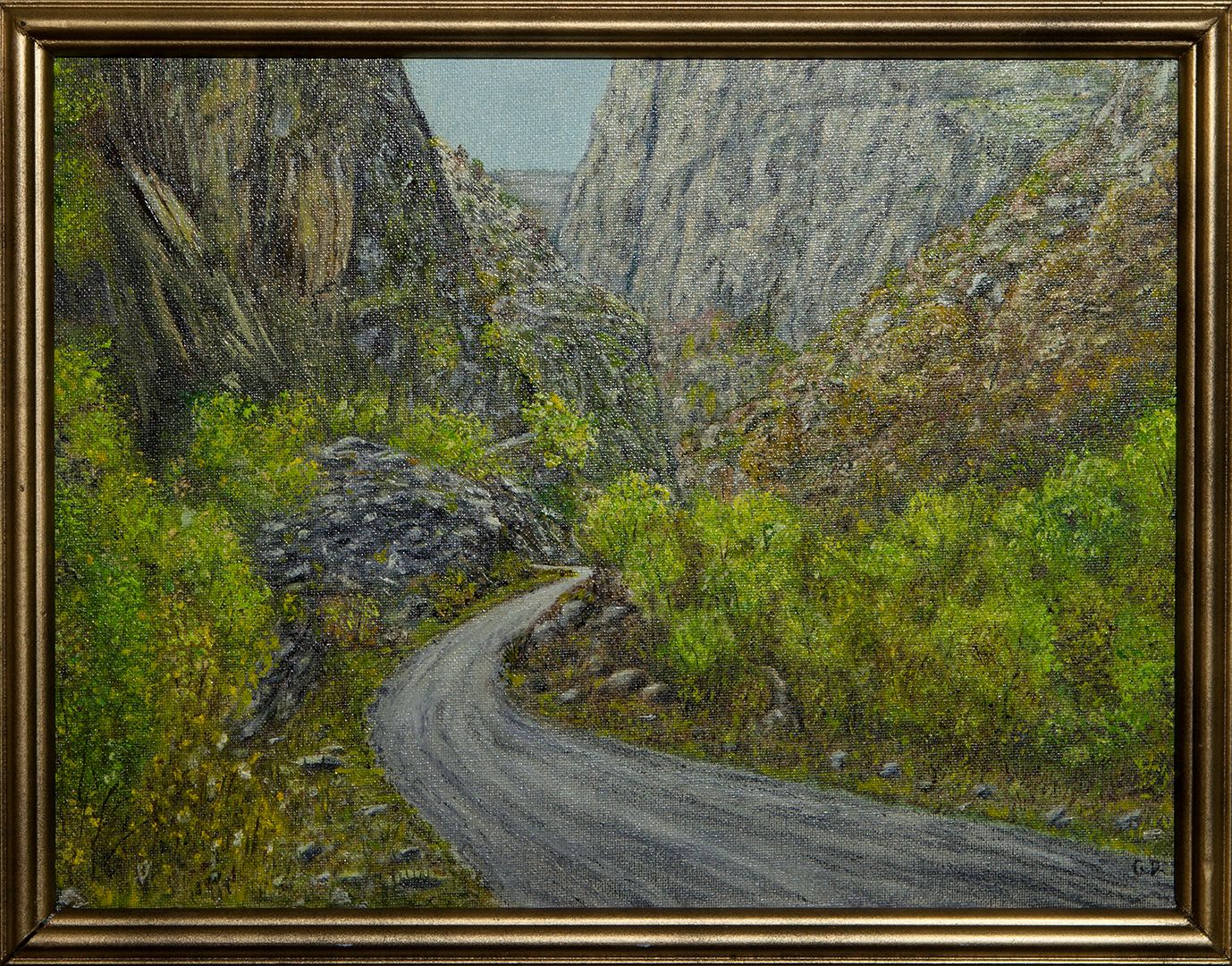 A narrow paved road curving between steep grey cliffs into a deep gorge, its slopes covered in green shrubs.