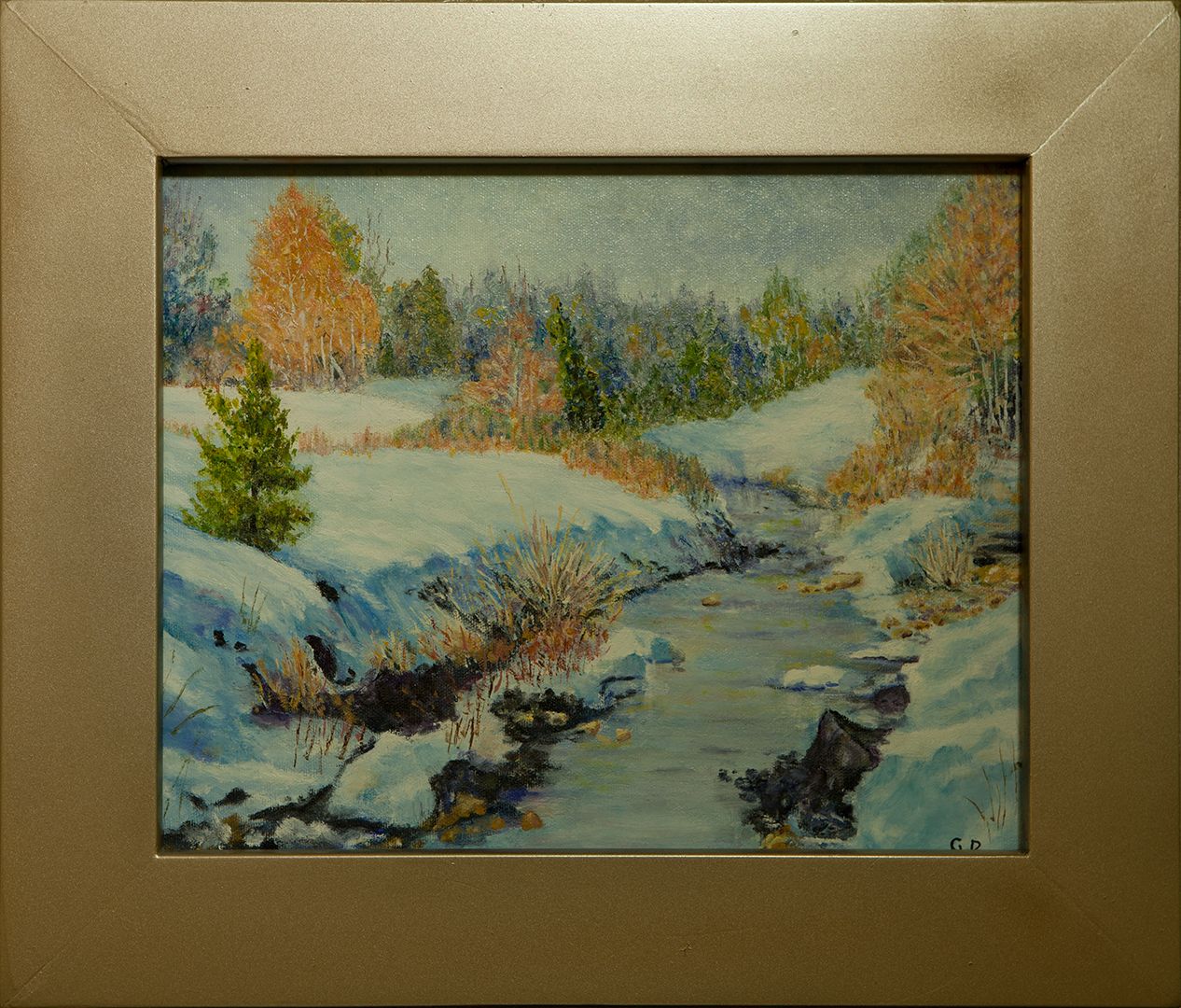 A stream winding through snow-covered banks, with a young spruce and trees still holding orange leaves.